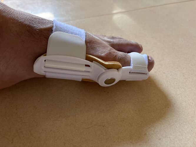 Vista lateral do corretor noturno para joanete mostrando o encaixe anatômico no dedão e o suporte com velcro